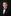 Young boy in a black suit with a purple bow tie against a dark background
