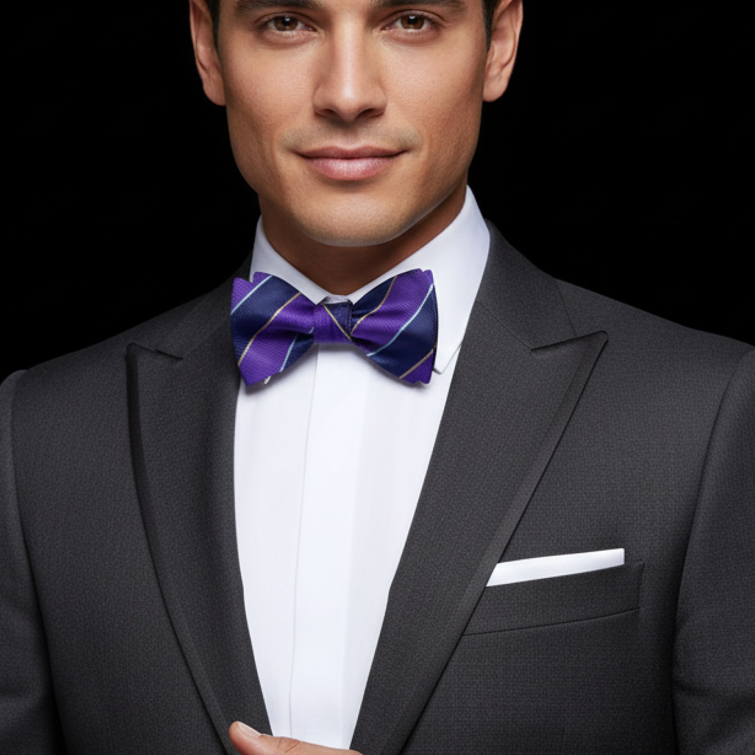 Man wearing a black suit with a white shirt and purple bow tie on a black background