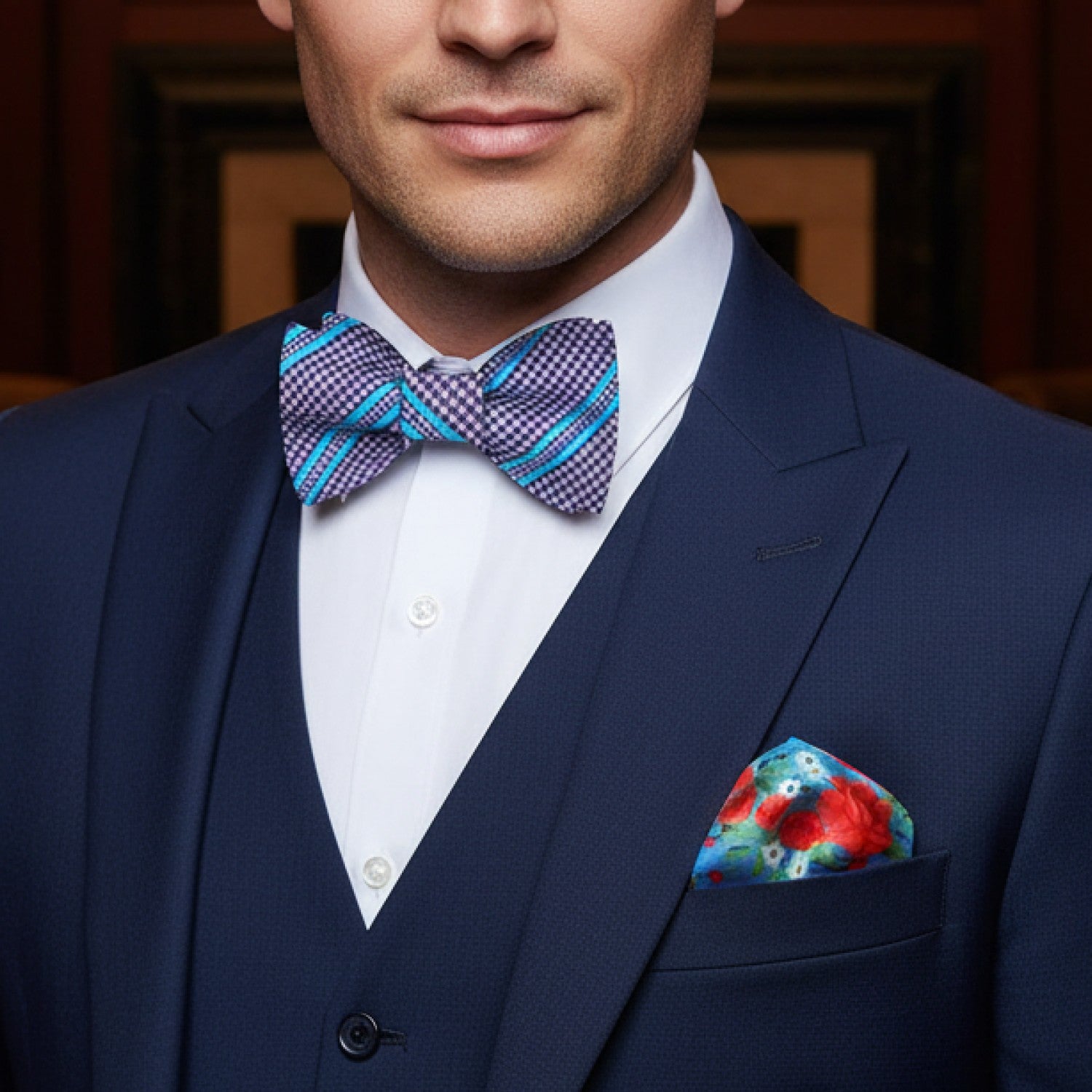 Man wearing a navy suit with a colorful bow tie and pocket square.
