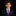 A young boy wearing a black suit jacket, white dress shirt, and a purple paisley patterned tie and pocket square, photographed against a solid black background.