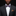 Man wearing a black suit with a purple bow tie and brown pocket square against a dark background