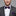 Man wearing a gray suit with a purple bow tie and pocket square on a gray background