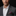 Man wearing a gray suit with a white shirt and purple checkered pocket square on a black background