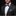 Man wearing a black suit with a purple plaid bow tie and pocket square on a dark background