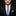 Man wearing a black suit with a floral tie and pocket square on a dark background