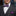 Man wearing a gray suit with a purple bow tie and pocket square, against a blurred indoor background.