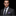 Man wearing a dark suit with a purple tie and pocket square on a black background