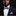 Man wearing a black suit with a purple bow tie and pocket square against a dark background