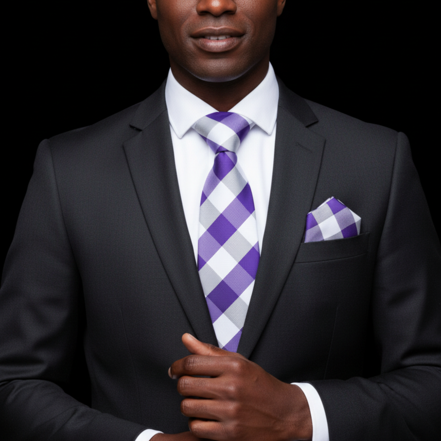 Man wearing a black suit with a purple and white checkered tie and pocket square on a black background
