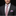 Man wearing a black suit with a patterned purple tie and pocket square on a black background