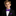 Young boy in a black suit with a purple bow tie and pocket square on a black background
