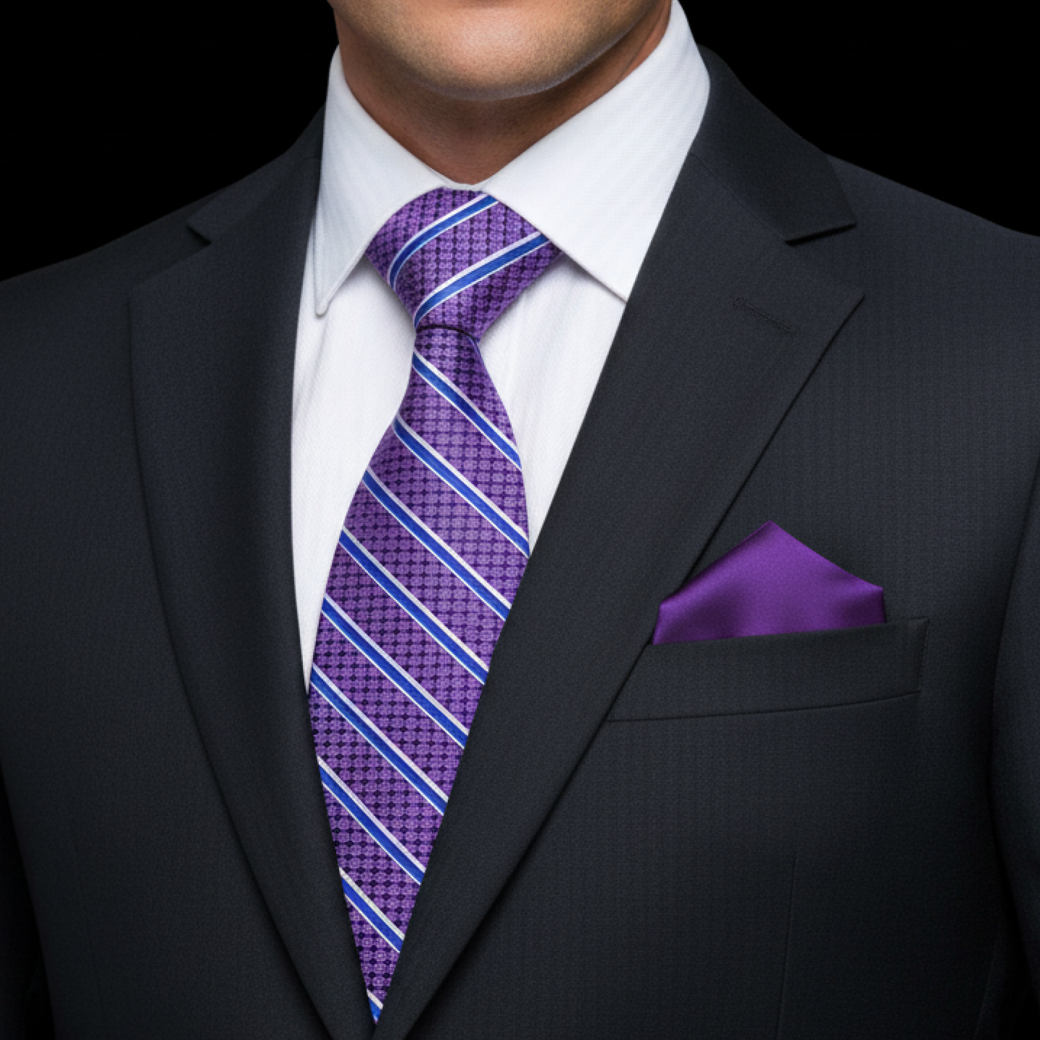 Man wearing a dark suit with a purple striped tie and purple pocket square on a black background