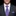 Man wearing a dark suit with a purple striped tie and pocket square on a black background