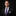 Man wearing a black suit with a purple tie and pocket square on a black background