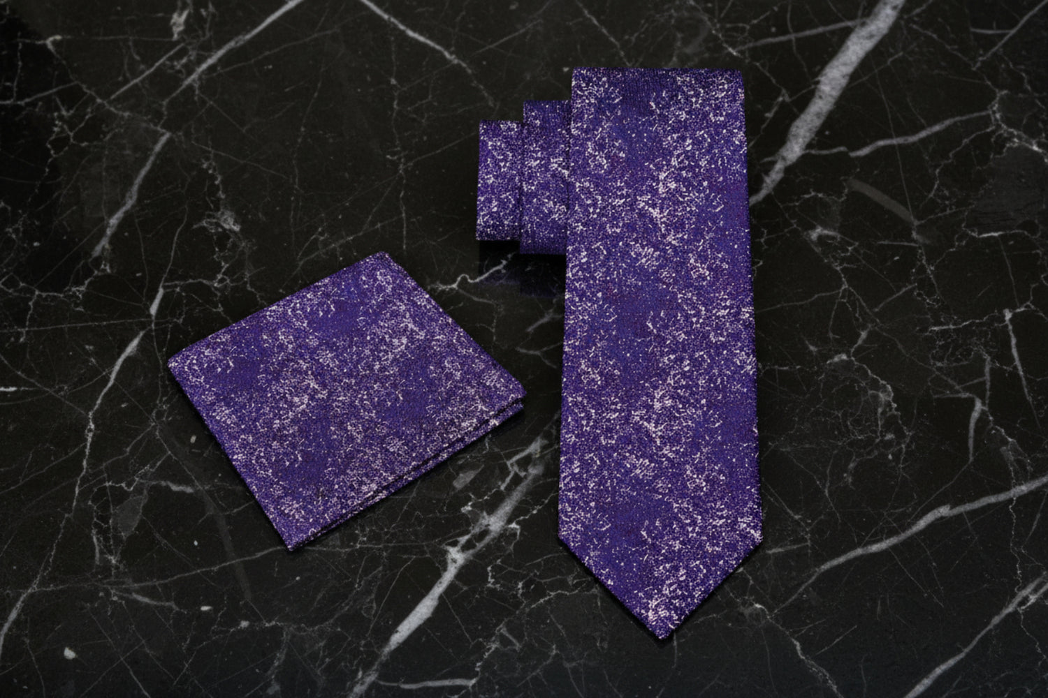 Purple tie and pocket square set on a black table