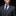 Man wearing a gray suit with a purple paisley tie and pocket square on a black background