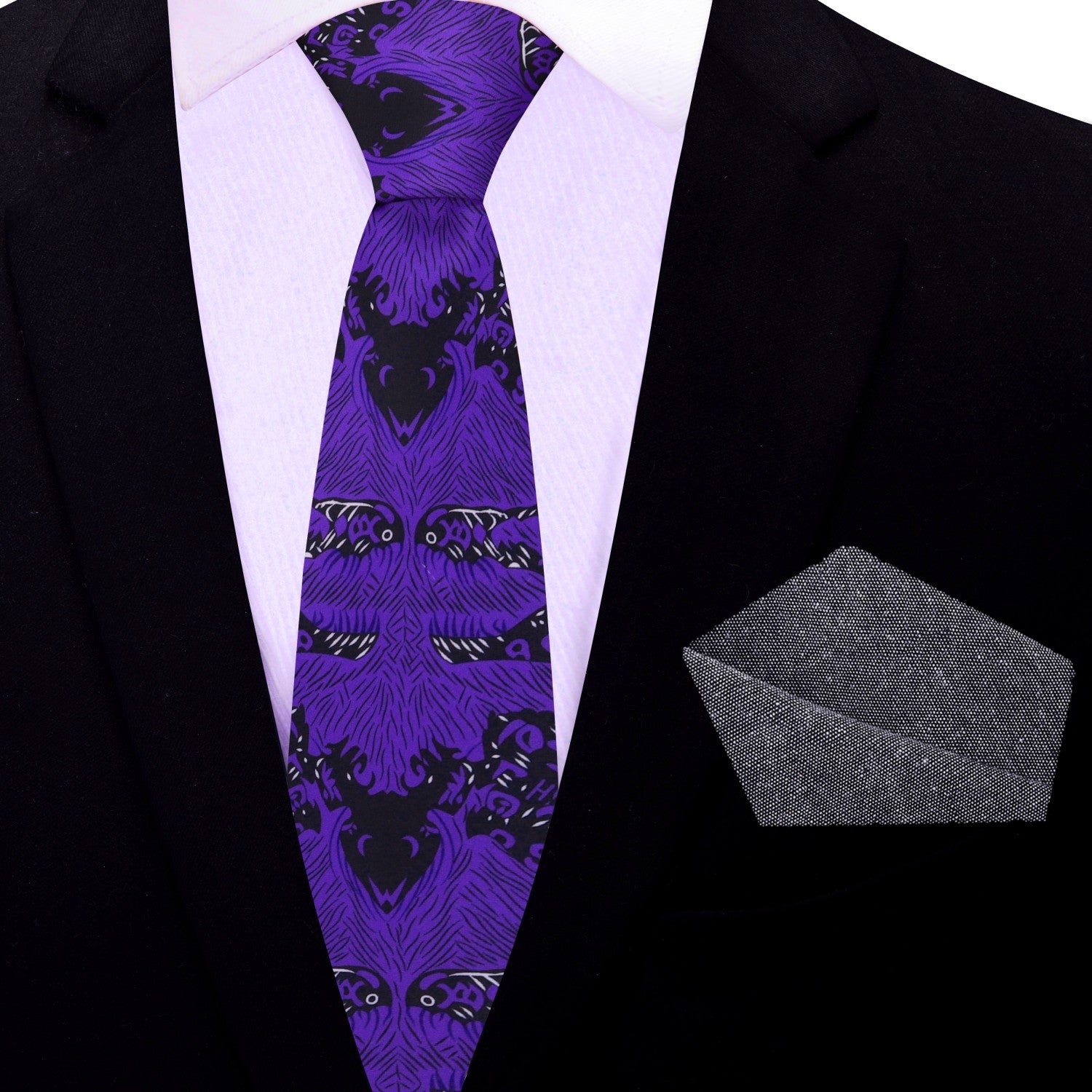 Purple patterned thin tie with a gray pocket square on a black suit jacket.