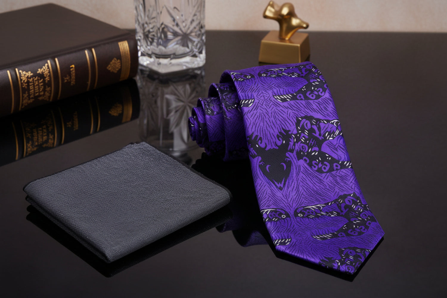 Purple tie with black leaf pattern and gray pocket square on a marble background