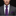 Man wearing a gray suit with a purple tie and pocket square on a black background