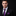 Man wearing a black suit with a purple tie and pocket square on a black background