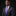 Man wearing a dark suit with a purple tie and pocket square on a black background