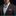 Man wearing a dark suit with a white shirt and red pocket square on a black background