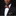Man wearing a black suit with a red bow tie and patterned pocket square on a dark background