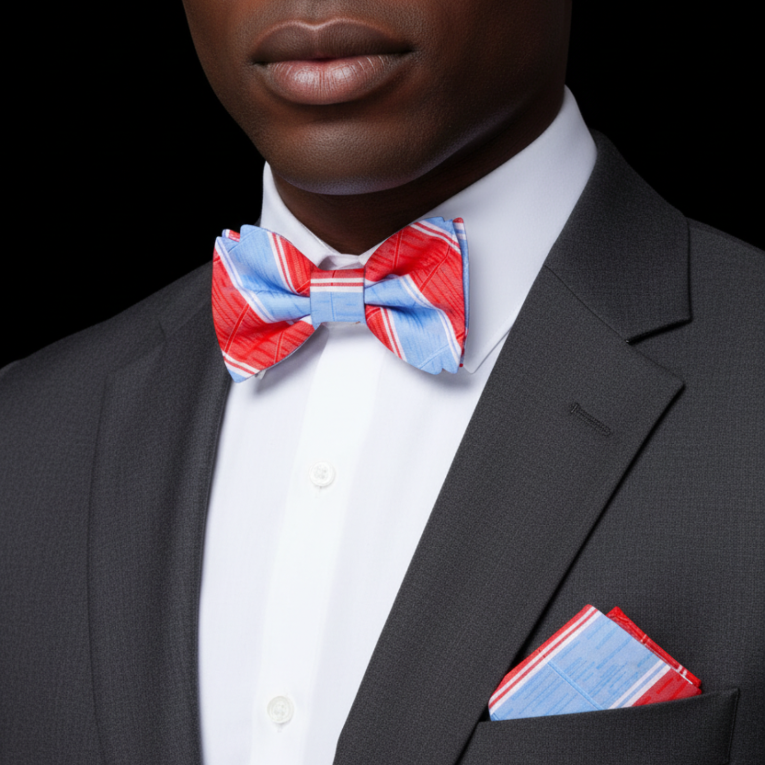 Man wearing a gray suit with a red, white, and blue bow tie and matching pocket square.
