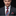 Man wearing a dark suit with a colorful paisley tie and pocket square on a black background