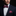 Man wearing a dark suit with a red and purple bow tie and pocket square against a black background