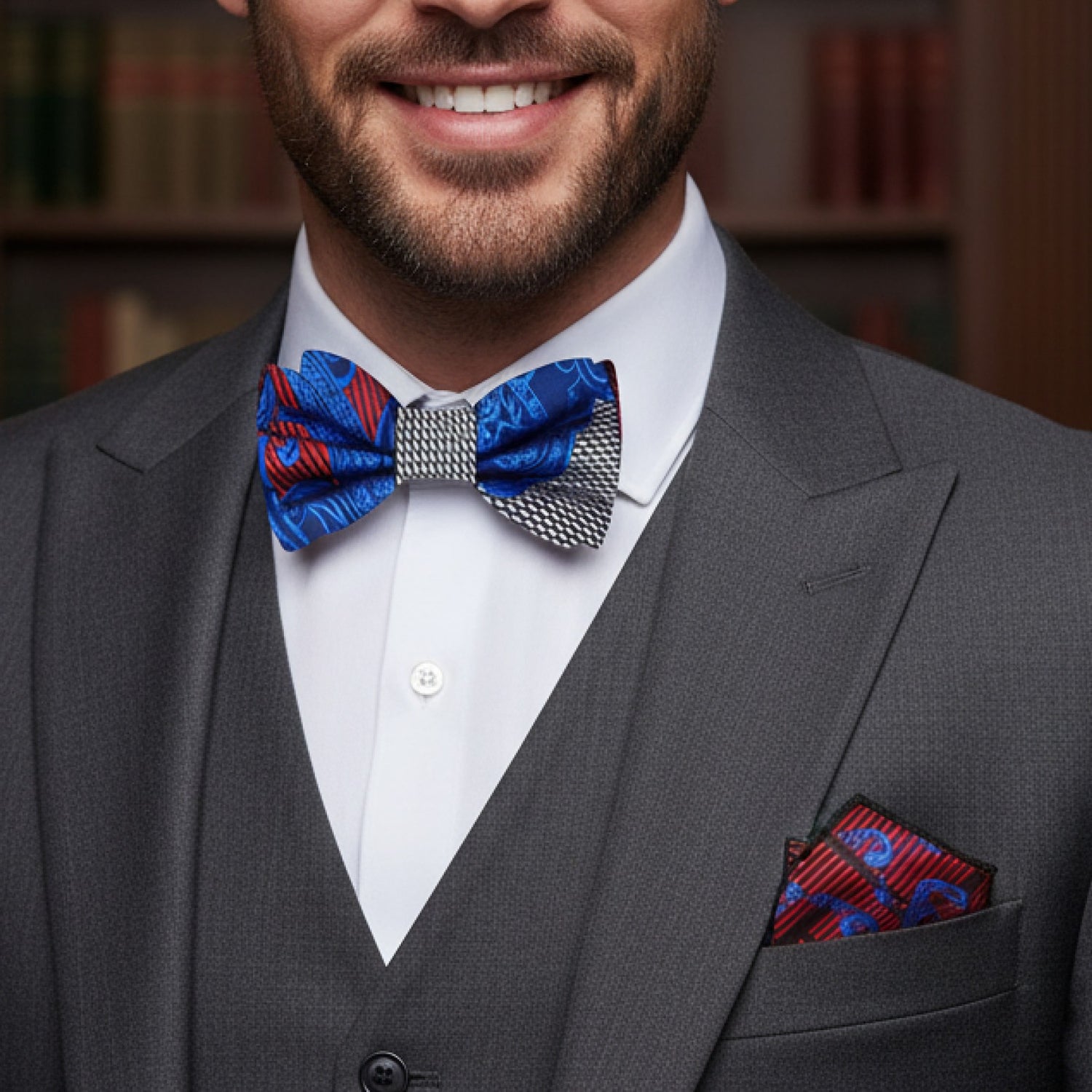 Man wearing a gray suit with a blue and red bow tie and matching pocket square.