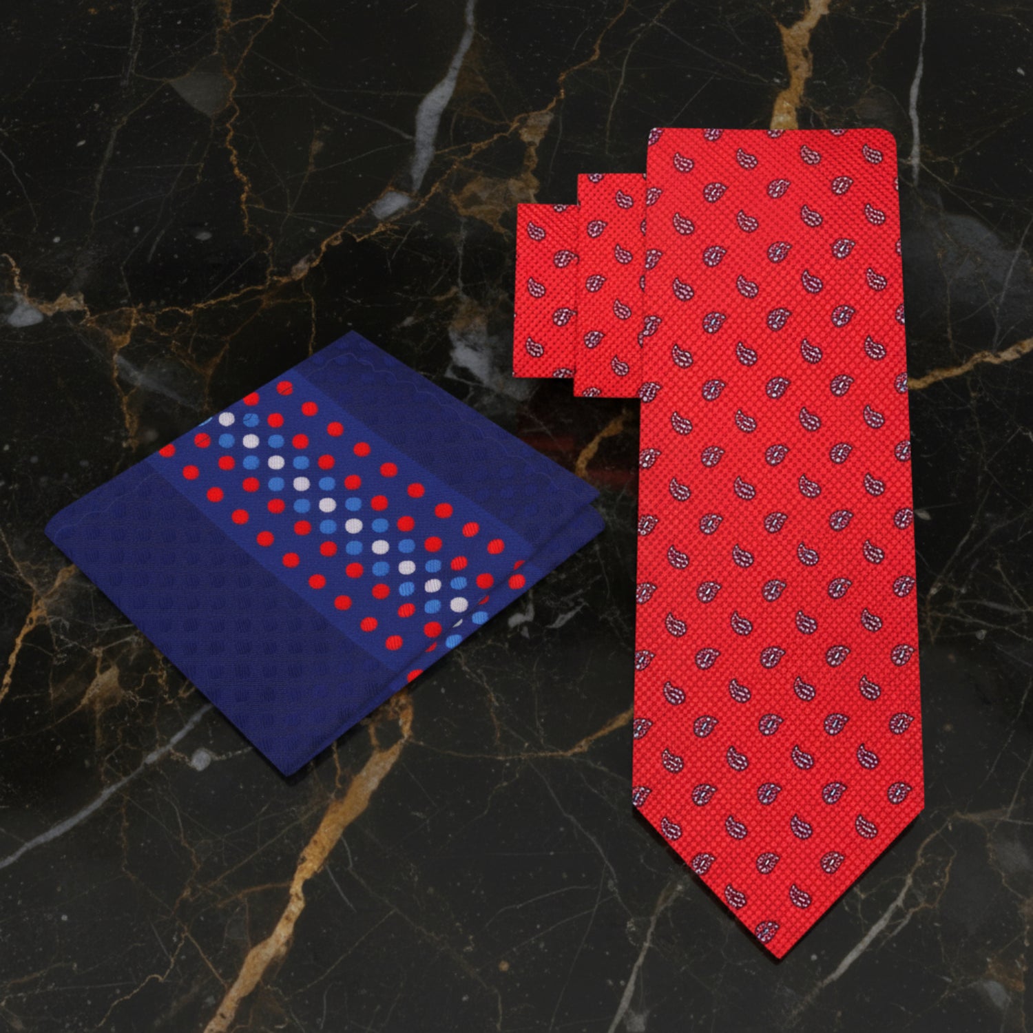 Red patterned tie and blue polka dot pocket square on a marble background