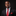 Man wearing a black suit with a red tie and pocket square on a black background