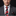 Man wearing a gray suit with a red and black striped tie against a black background