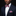 Man wearing a navy suit with a red, white, and blue bow tie and pocket square against a black background