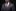 Man wearing a gray suit with a red patterned tie and pocket square on a black background
