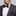 Man wearing a gray suit with a red patterned bow tie and pocket square on a light gray background