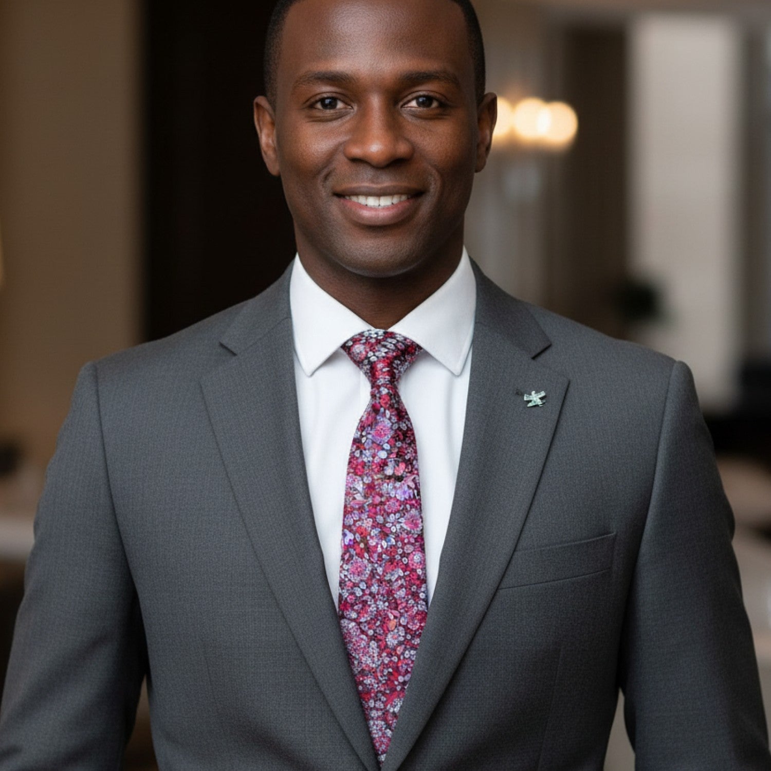 Man wearing a gray suit with a colorful tie in an indoor setting