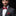 Man wearing a gray suit with a red bow tie and pocket square on a black background