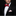 Man wearing a black tuxedo with a red bow tie and pink handkerchief on a dark background
