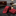 Red patterned tie and pocket square on a dark surface with books and a lamp in the background.