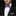 Man wearing a black suit with a white shirt and a red, white, and blue bow tie on a black background