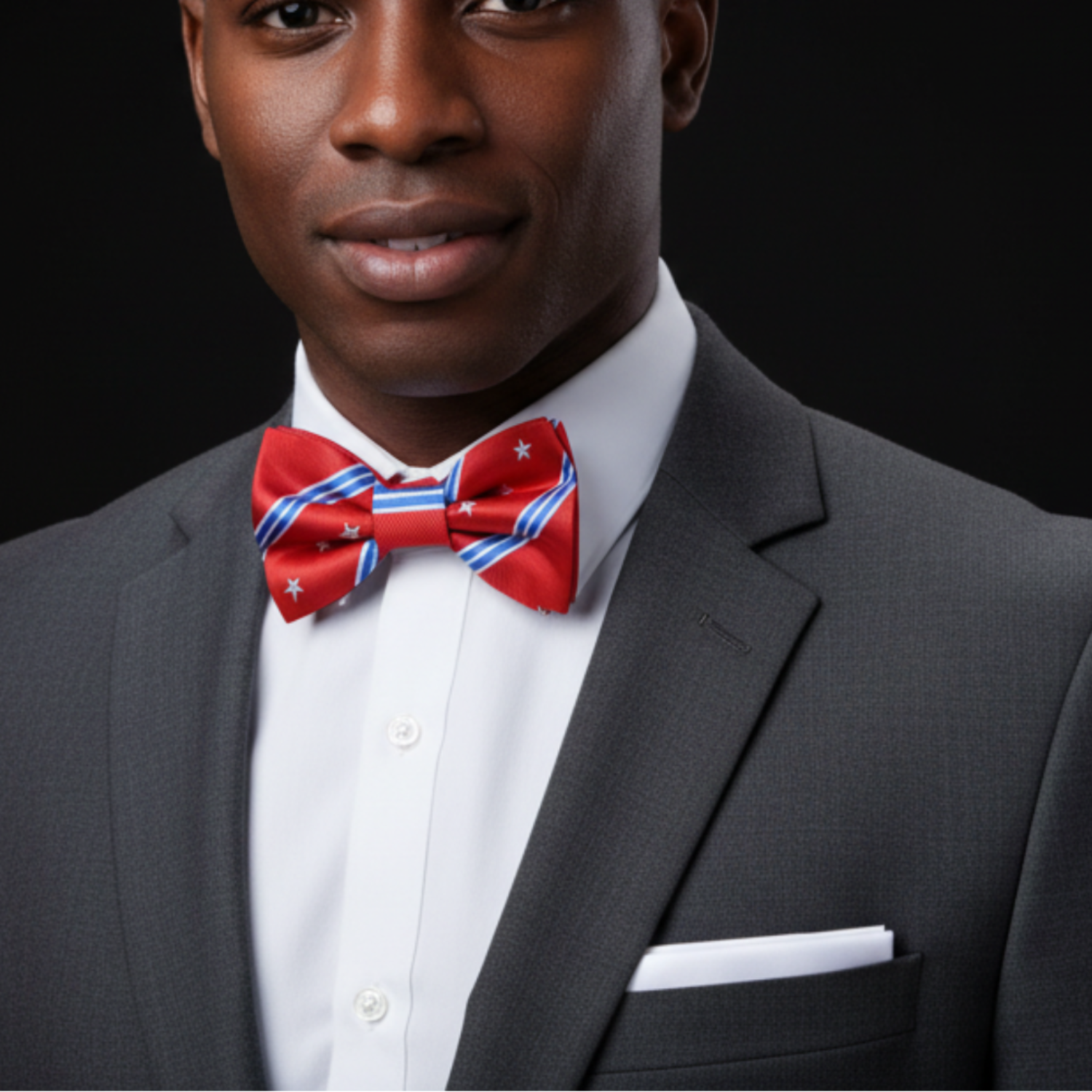 Man wearing a gray suit with a red bow tie featuring white stars on a black background