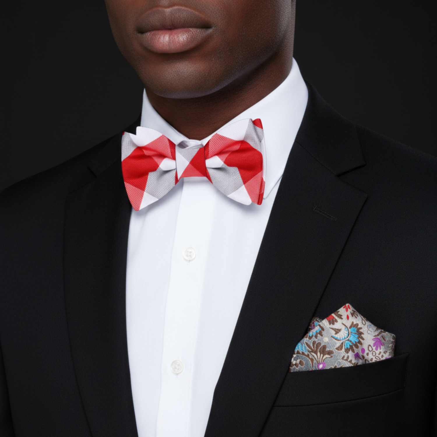 Man wearing a black suit with a red and white bow tie and patterned pocket square.