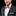 Man wearing a black suit with a white shirt and a red patterned bow tie on a black background
