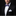 Man wearing a black suit with a white shirt and colorful bow tie on a dark background