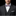 Man wearing a gray suit with a white shirt and red, blue, and white checkered bow tie on a black background