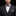 Man wearing a black suit with a red, white, and blue bow tie and pocket square against a dark background