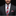 Man wearing a dark suit with a red and gray plaid tie and pocket square on a black background