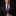 Man wearing a black suit with a red and blue floral tie and matching pocket square on a dark background